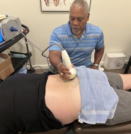 Dr. Gerdine applying a shockwave handpiece to a patient's lower back
