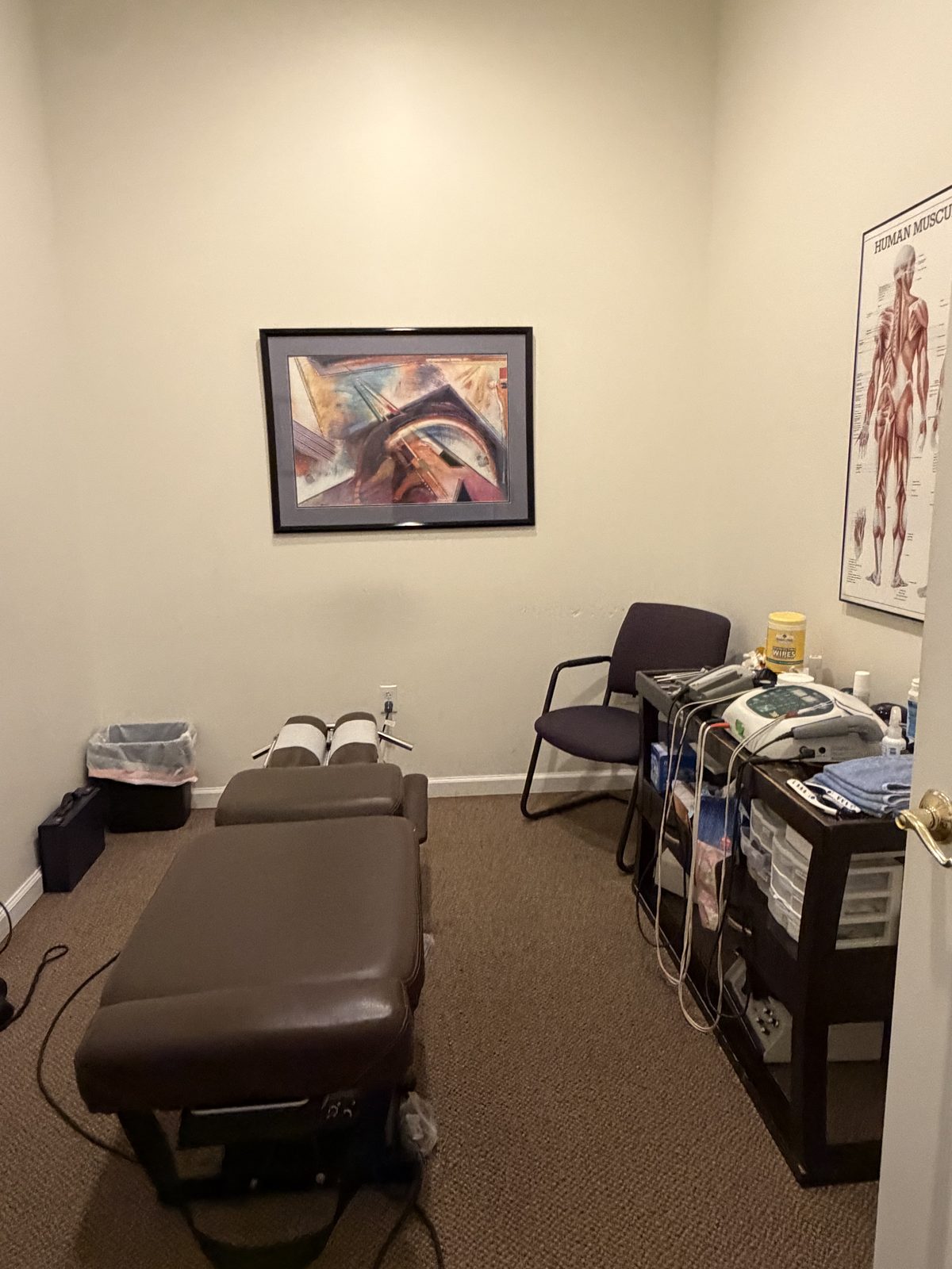 Adjustment room with padded chiropractic table and therapy equipment