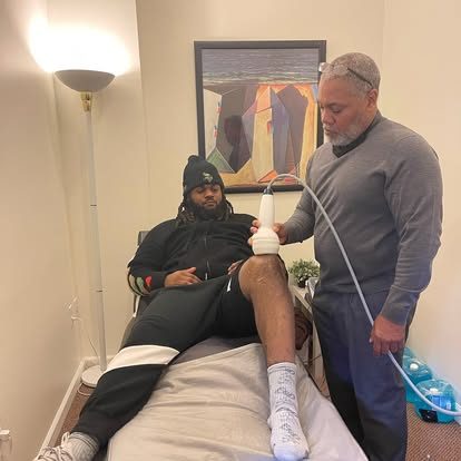 Dr. Gerdine treating a reclining patient's knee with a therapy device