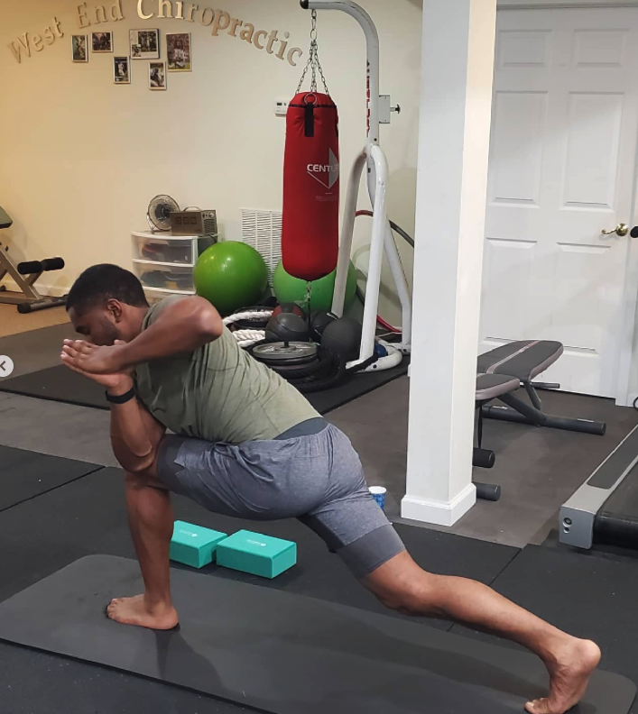 Patient doing a kneeling hip flexor stretch in the West End Chiropractic rehab gym