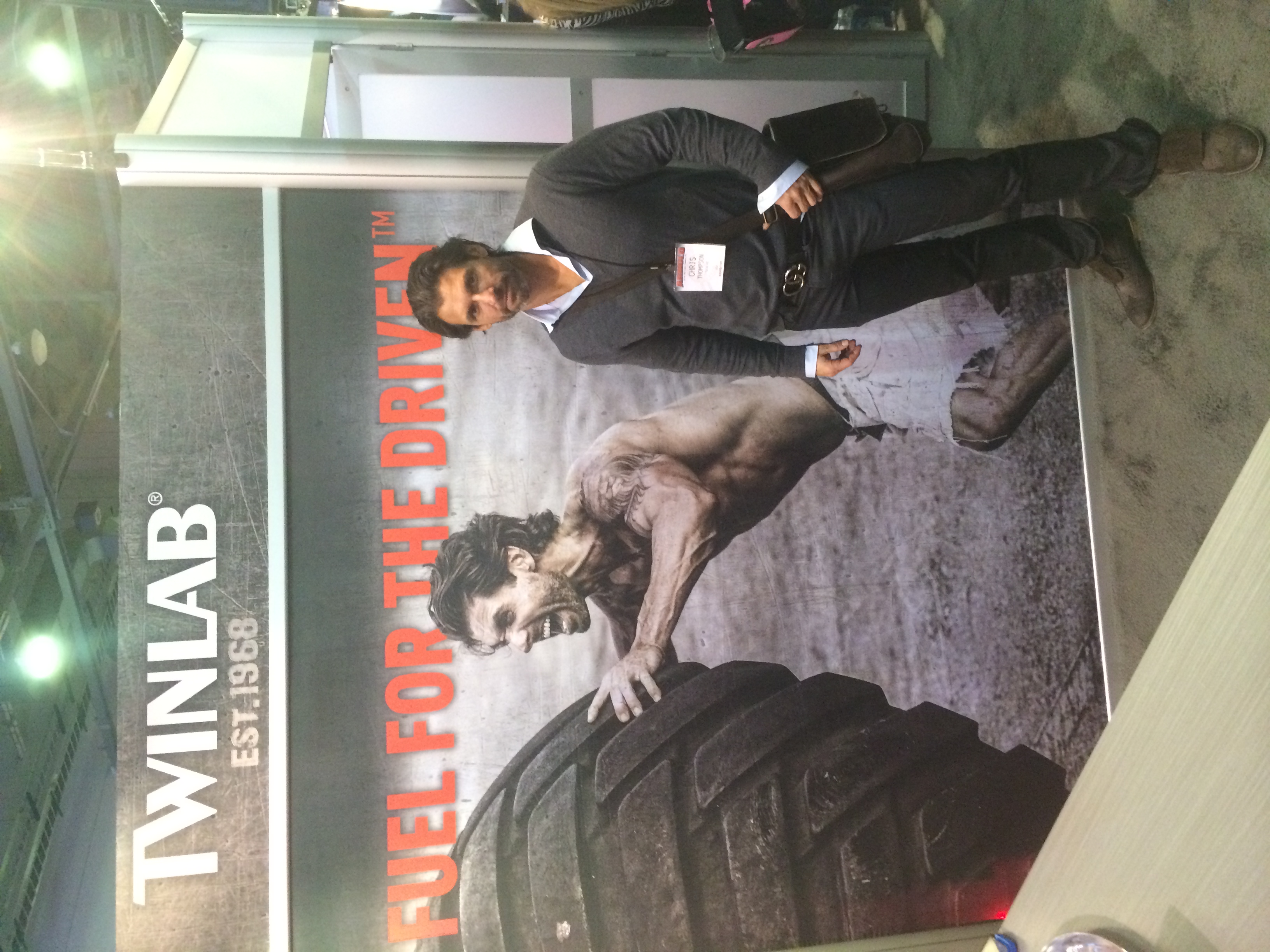 Christopher Thompson at the Twinlab booth beside his tire-flip campaign photograph