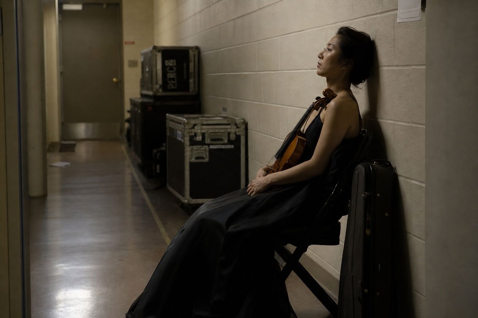 Classical musician sitting alone backstage after a performance in a quiet reflective moment Classical musician sitting alone backstage after a performance in a quiet reflective moment