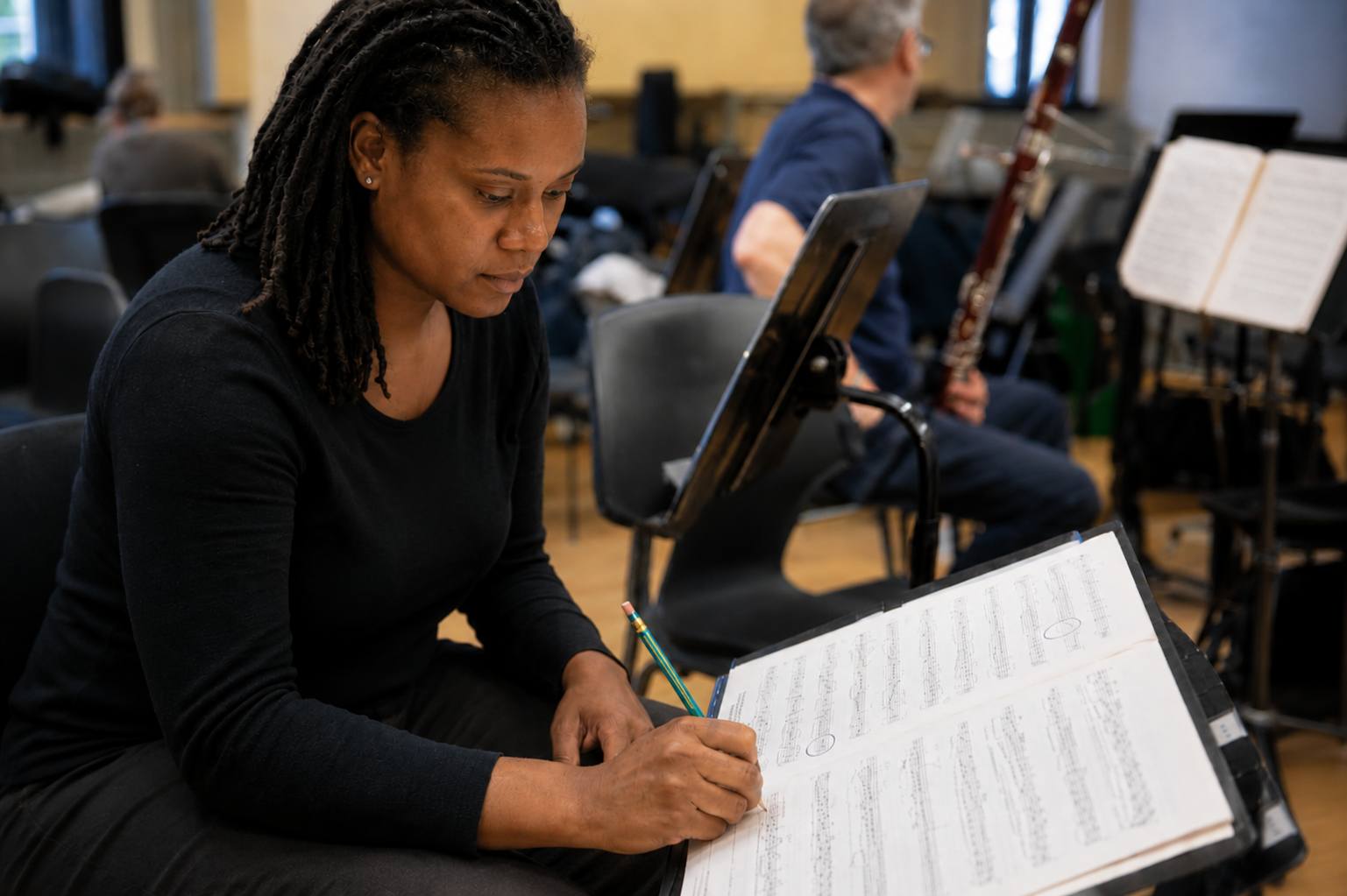 Orchestral musician focused while marking detailed notes on a score during rehearsal preparation Orchestral musician focused while marking detailed notes on a score during rehearsal preparation