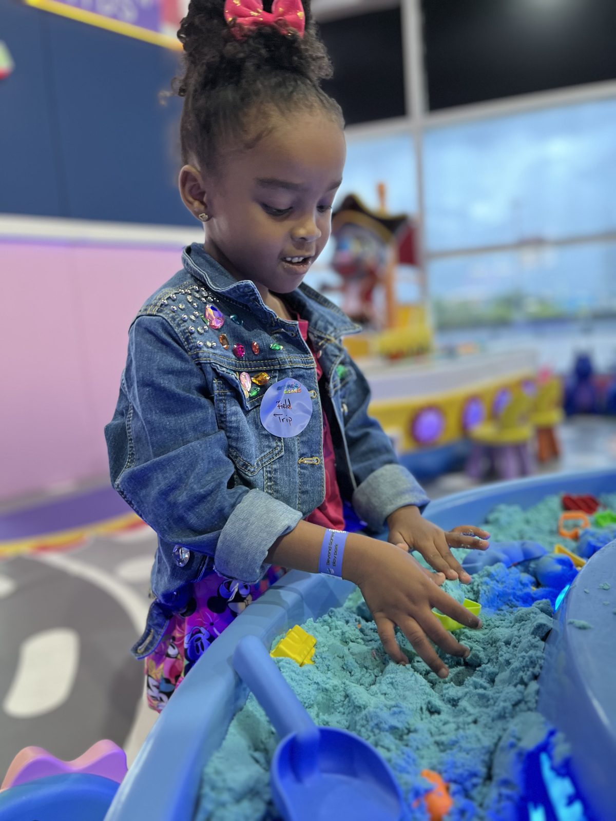 Child playing with kinetic sand at a light-up sensory table