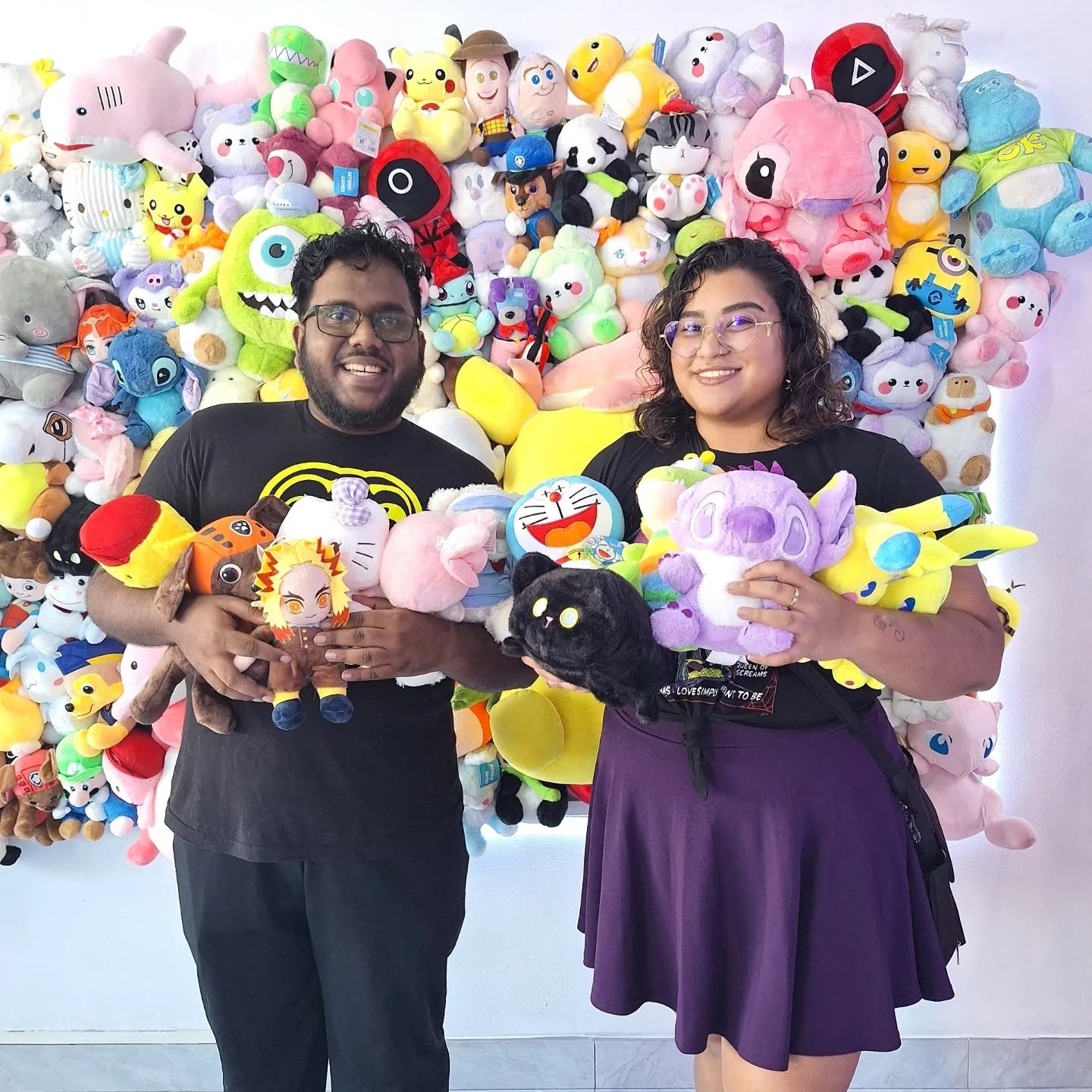 Couple holding armfuls of plushie prizes