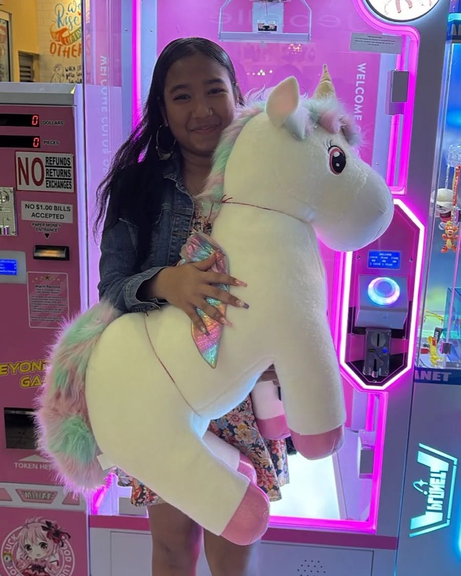Girl with a unicorn plush at a claw machine