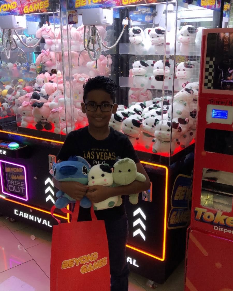Boy with an armful of plushie prizes by the claw machines