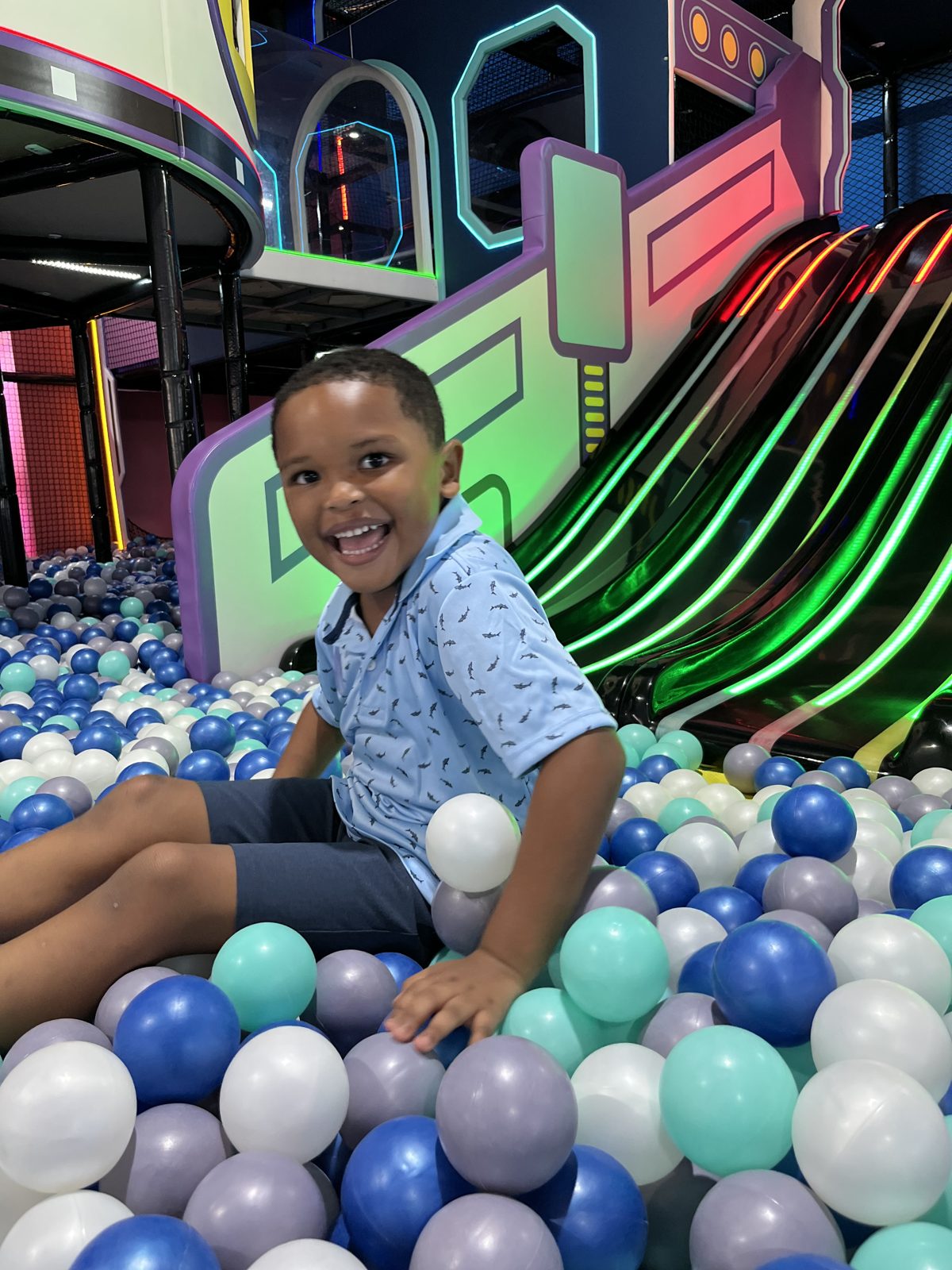 Boy smiling in the ball pit near the slides