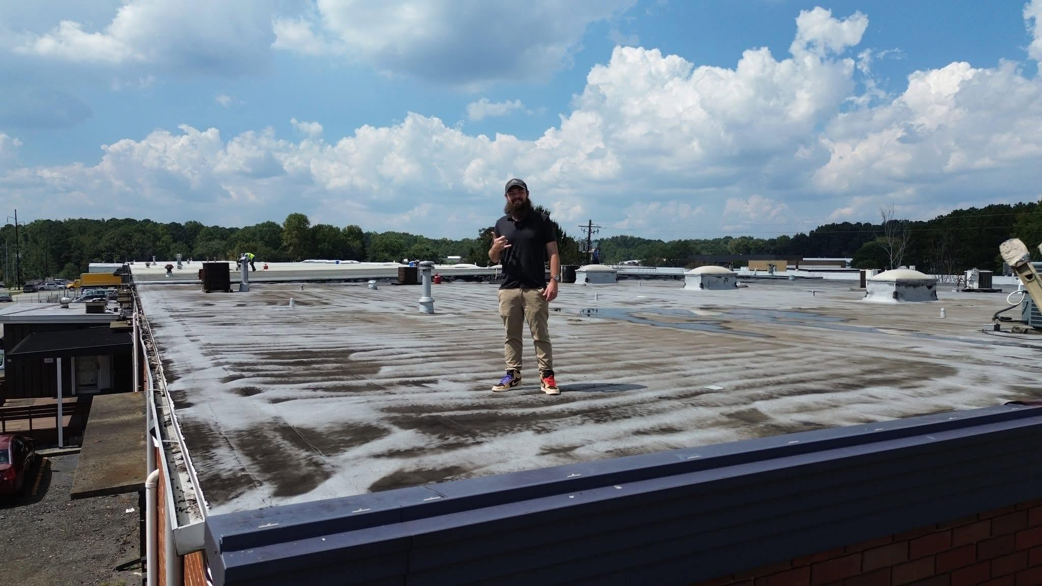 Joa Barron standing on a large commercial flat roof under a blue sky