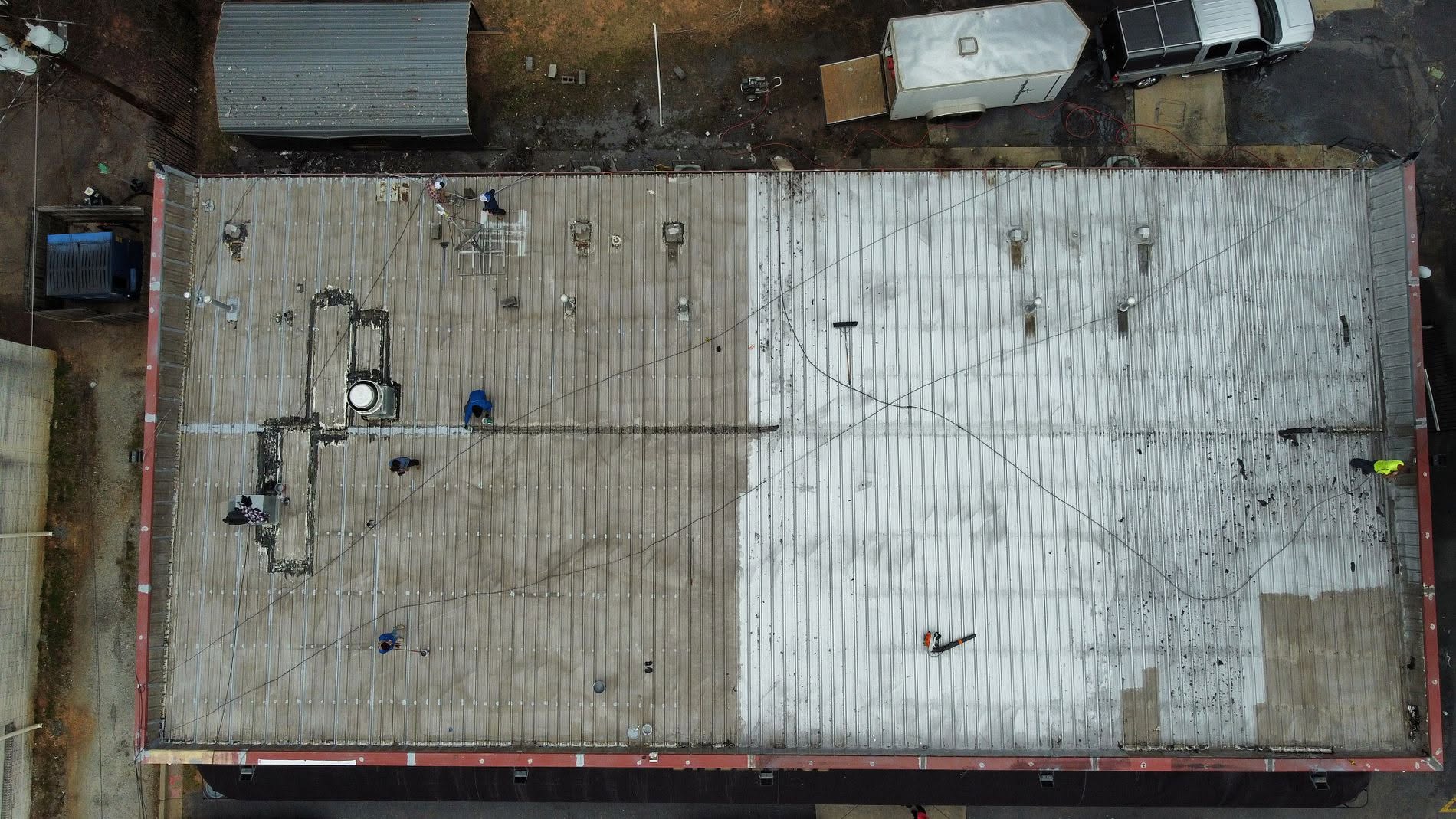 Drone view of a commercial roof job in progress with crew working