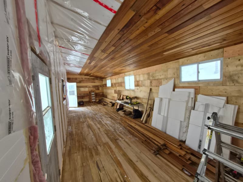 “Interior of off-grid shelter with cedar ceiling installed and plywood walls before painting during winter build “Interior of off-grid shelter with cedar ceiling installed and plywood walls before painting during winter build