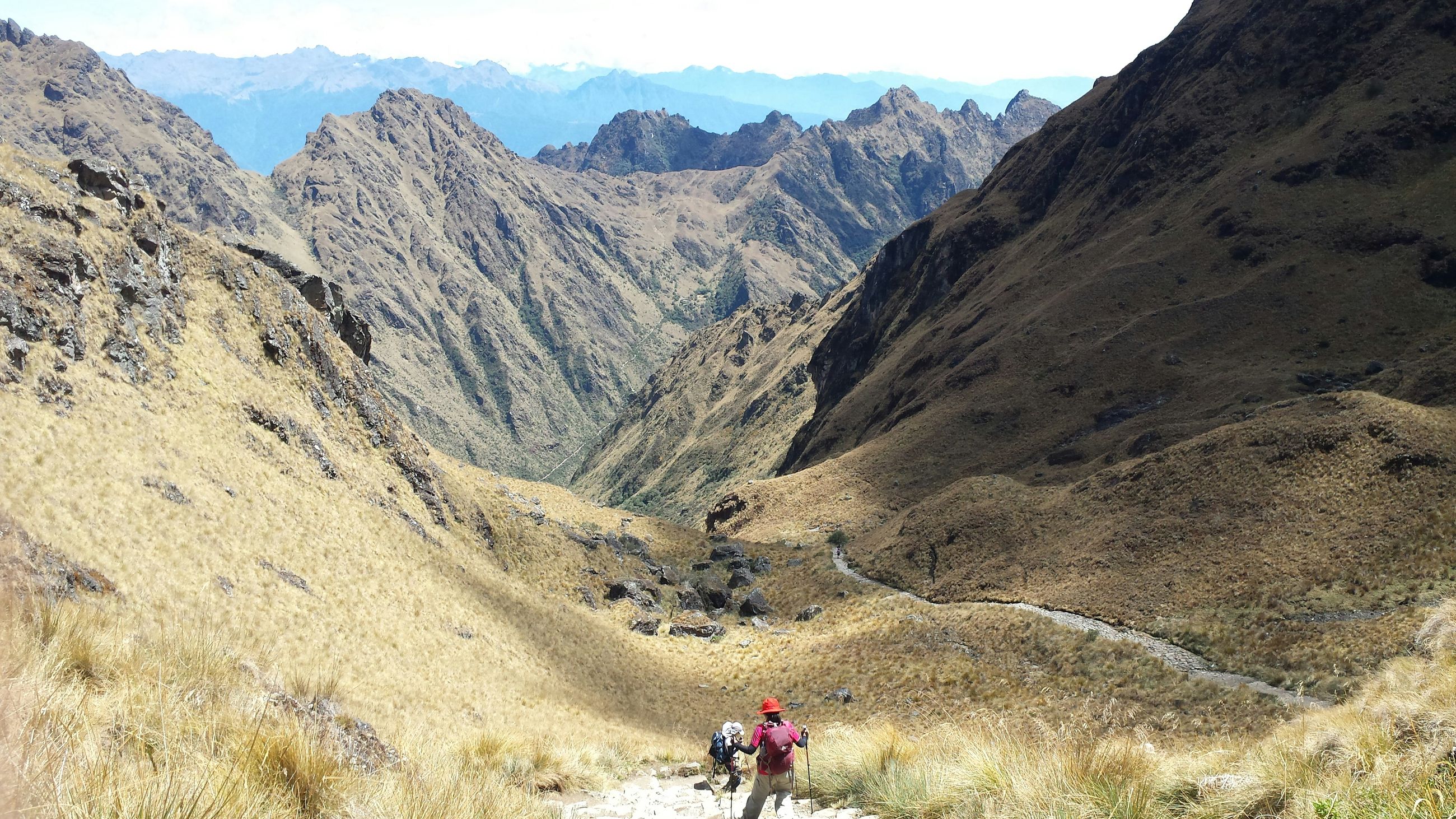 Hikers walking the Inca Trail down a wide Andean valley