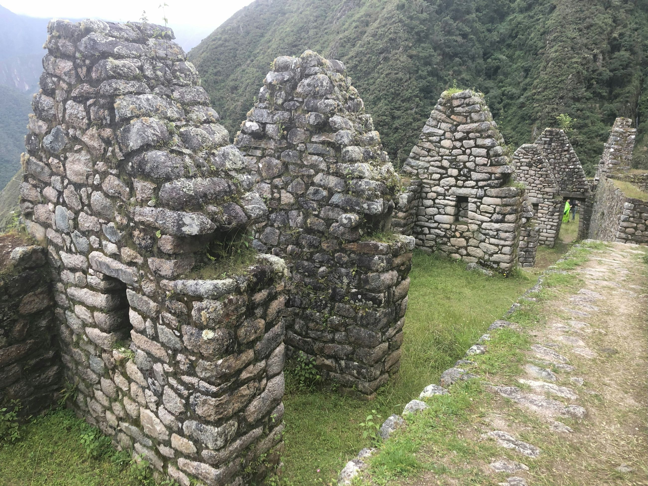 Inca stone ruins beside the trail in green mountains