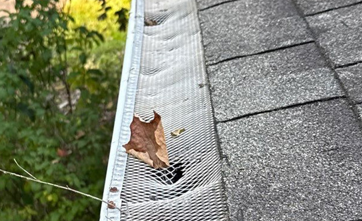 Hail-dented aluminum gutter cover on Minnesota home inspected by Honest Exteriors