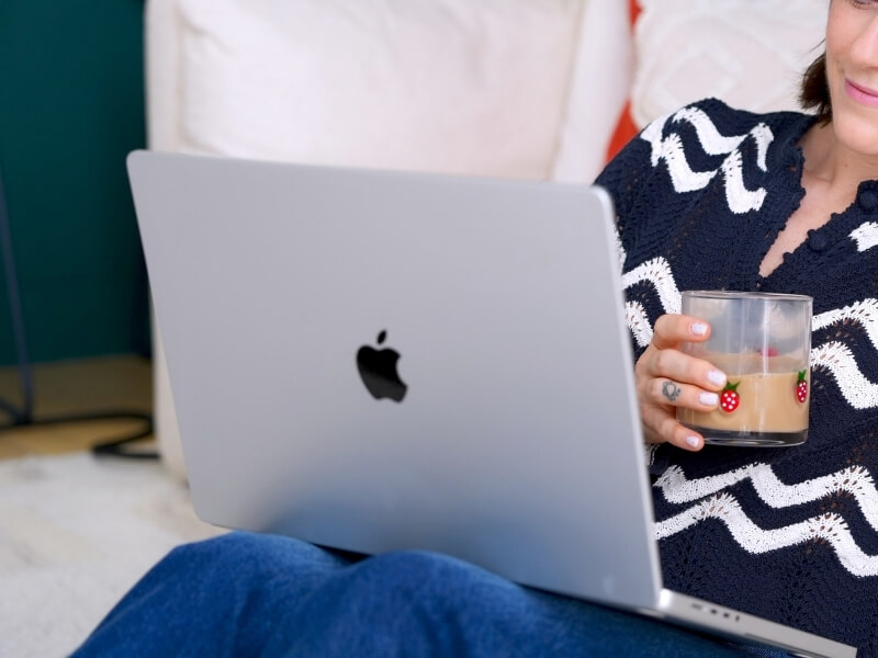 Laptop on lap with lex holding cup of coffee