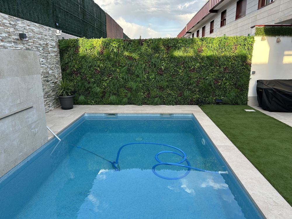 Piscina con jardín vertical y césped