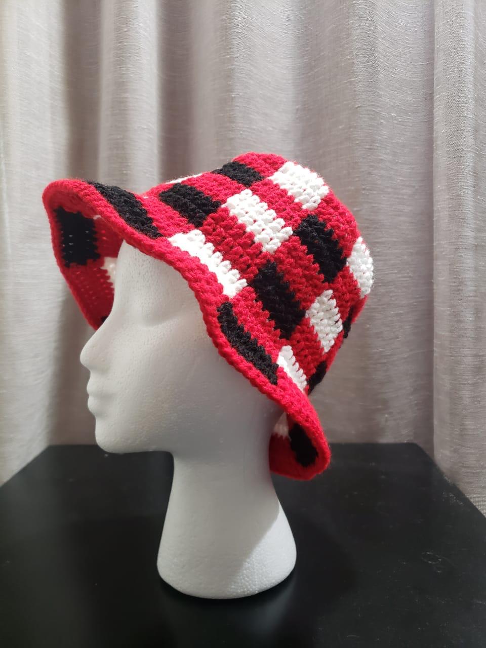 Red, black and white check crochet bucket hat, shown on a mannequin head