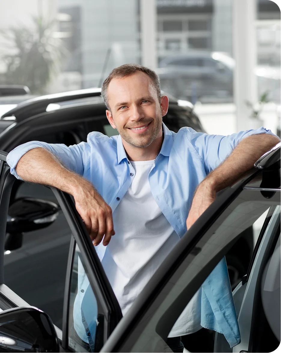 A satisfied client standing next to a vehicle outdoors.