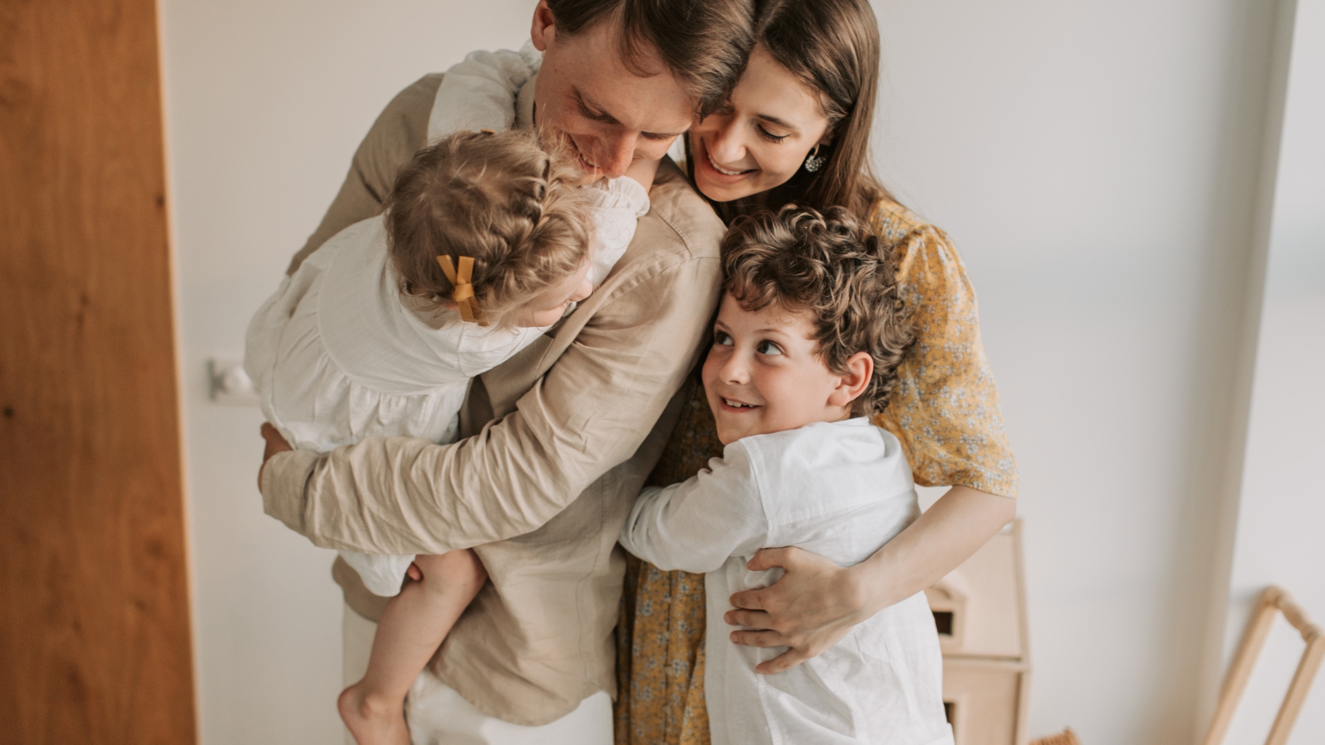 A mother and father hugging their two young children