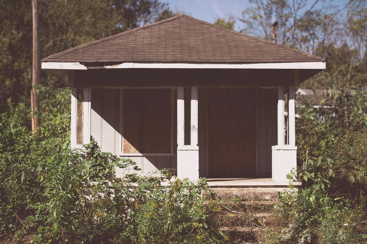 Weathered Austin bungalow with overgrown yard — the kind of house we buy as-is