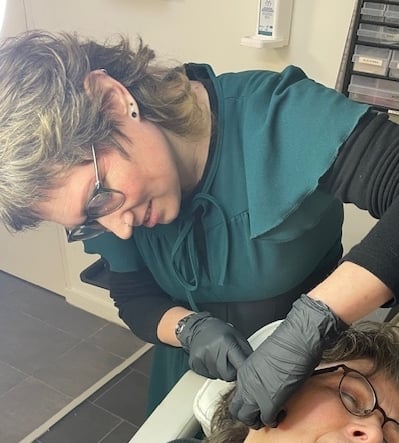 Piercing specialist Marja zet een oorbel piercing bij een klant in Iris Tattoo Art Deventer