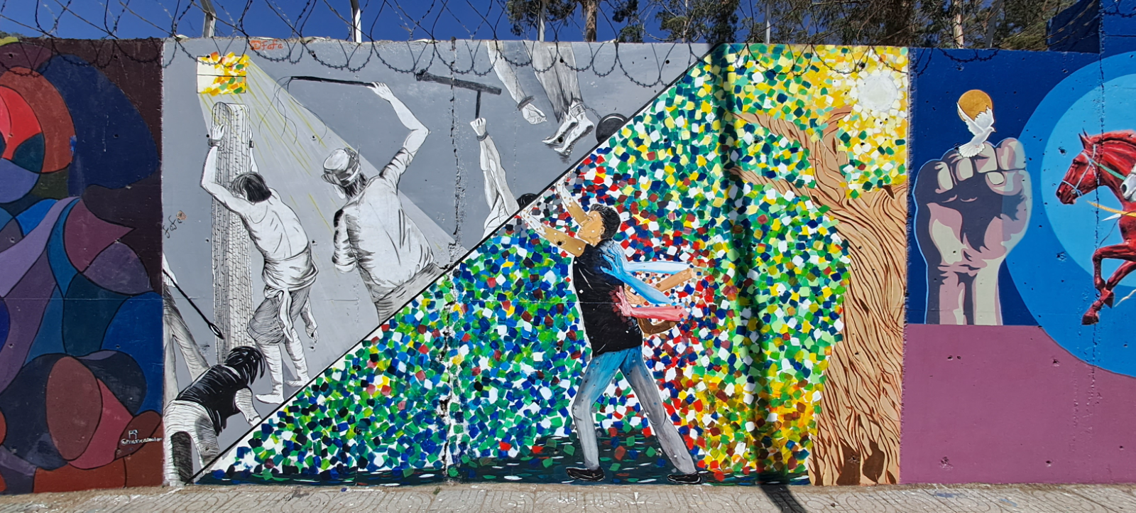 A colorful mural of a man reaching into a burst of color beside a tree