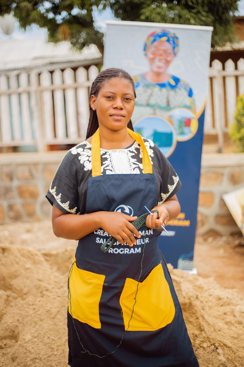 A woman in an UBUCHANGE apron holds her crochet work