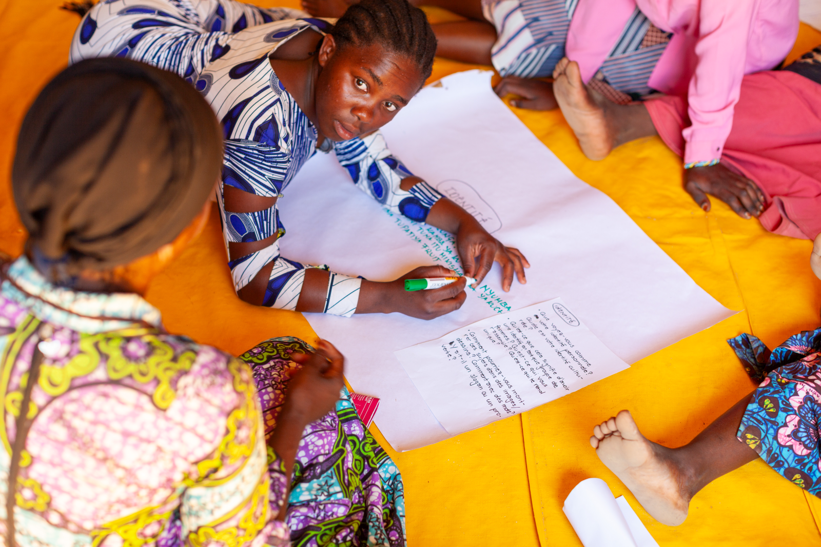 Women draw and write on large sheets of paper during the design session