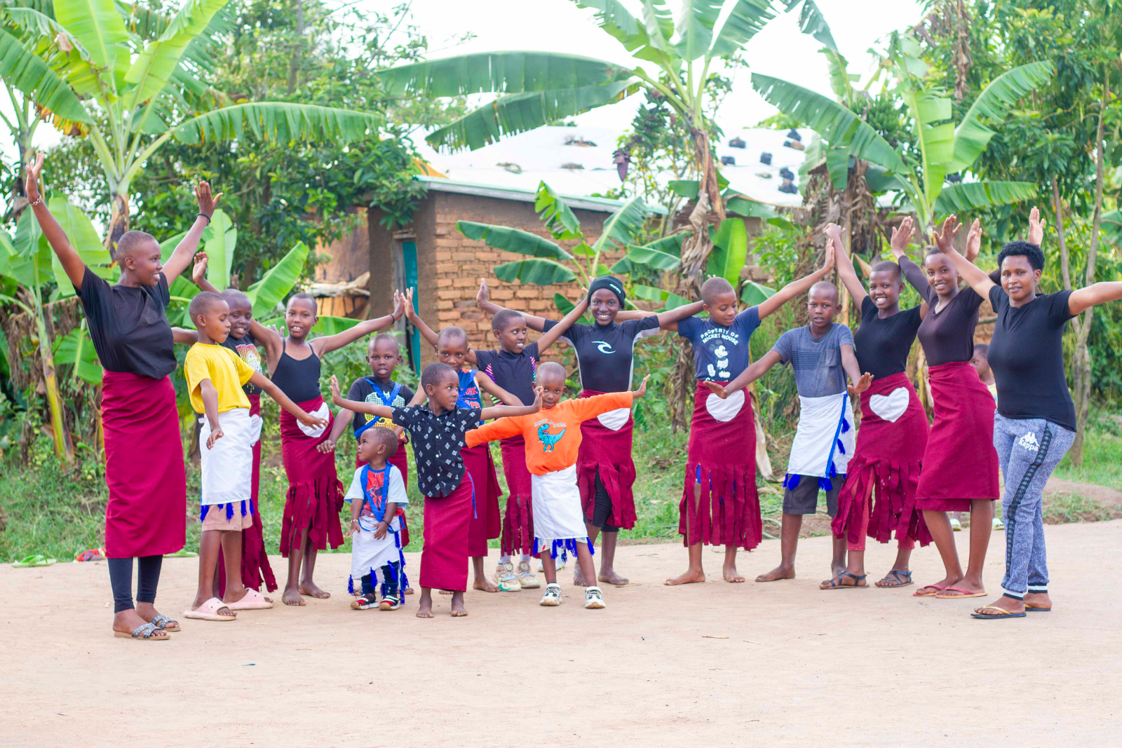 Children and community members dance together outside