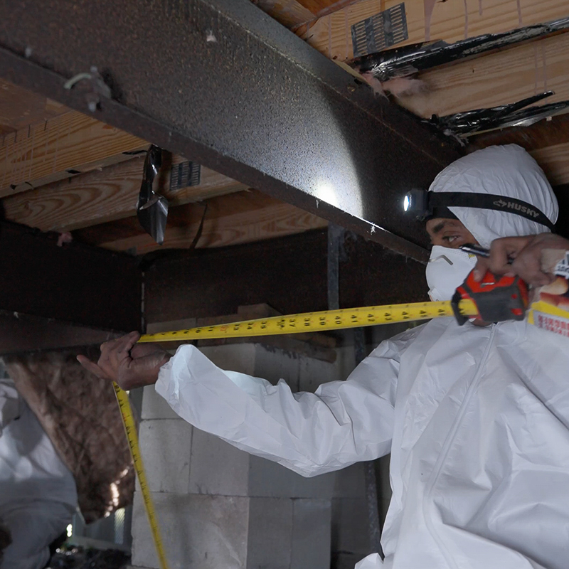 A technician from Vapor Barrier Bonita Springs installing a new, thick white vapor barrier under a mobile home in Bonita Springs, FL.