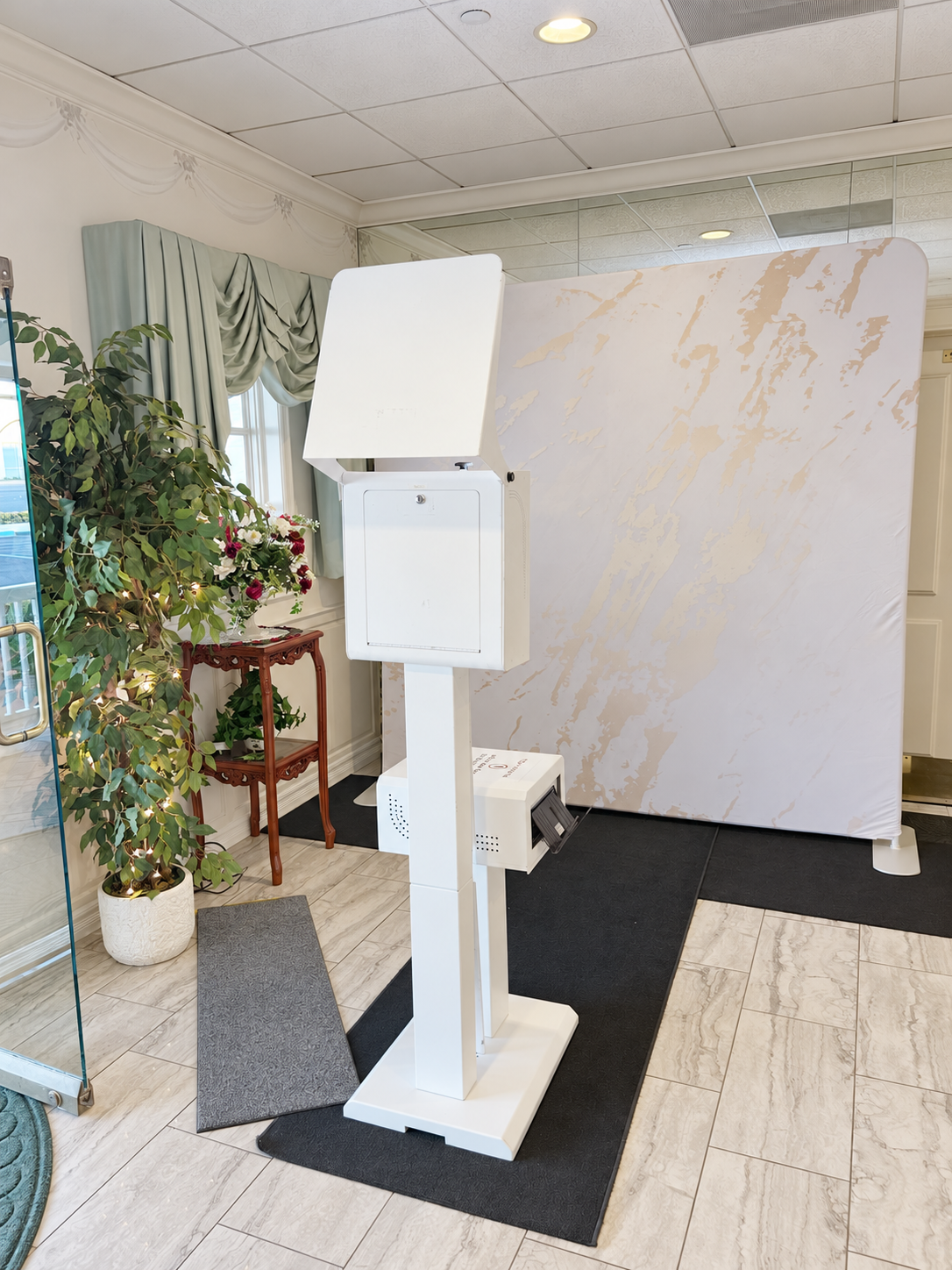 White open-air photo booth and printer with a gold-and-white marble backdrop at The Garden Room in La Habra