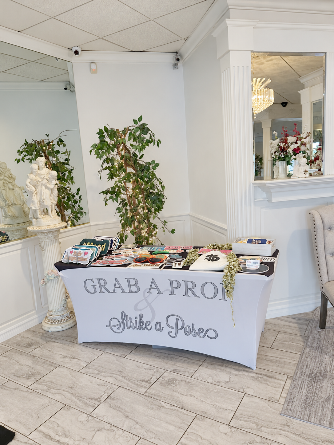 Photo booth props table with colorful signs and oversized glasses at The Garden Room quinceañera