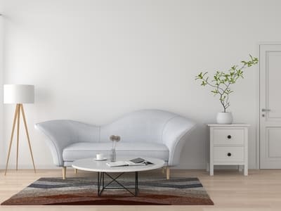 Modern living room with a sleek white sofa, a minimalist coffee table, a tall floor lamp, and a small white side table with a potted plant, highlighting a clean and simple design aesthetic.