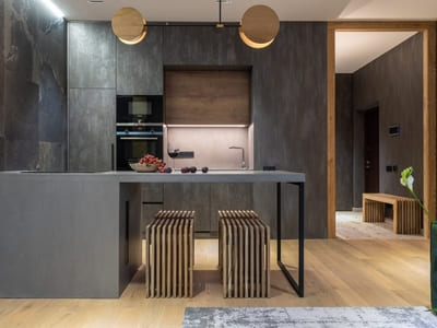 Modern kitchen with dark, textured walls, a sleek island with bar stools, contemporary lighting, and minimalist decor, emphasizing a sophisticated, industrial style.