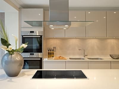 Modern kitchen with high-gloss cabinets, a glass range hood, and minimalist decor, showcasing a sleek and sophisticated cooking space.