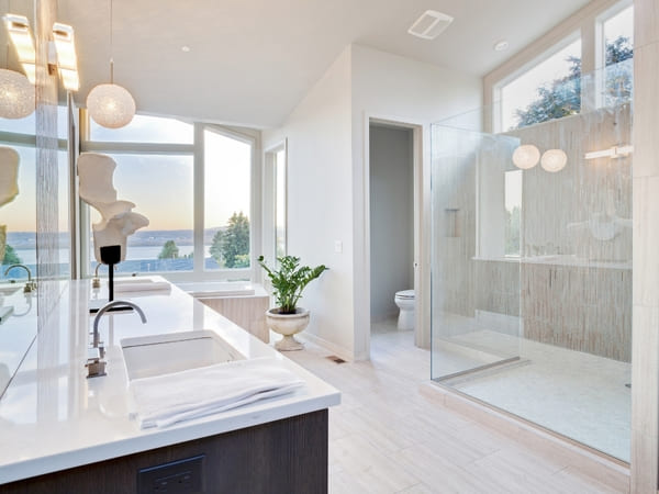 Luxurious bathroom with large windows, a spacious glass shower, and a double vanity, offering a breathtaking view and modern, elegant finishes.