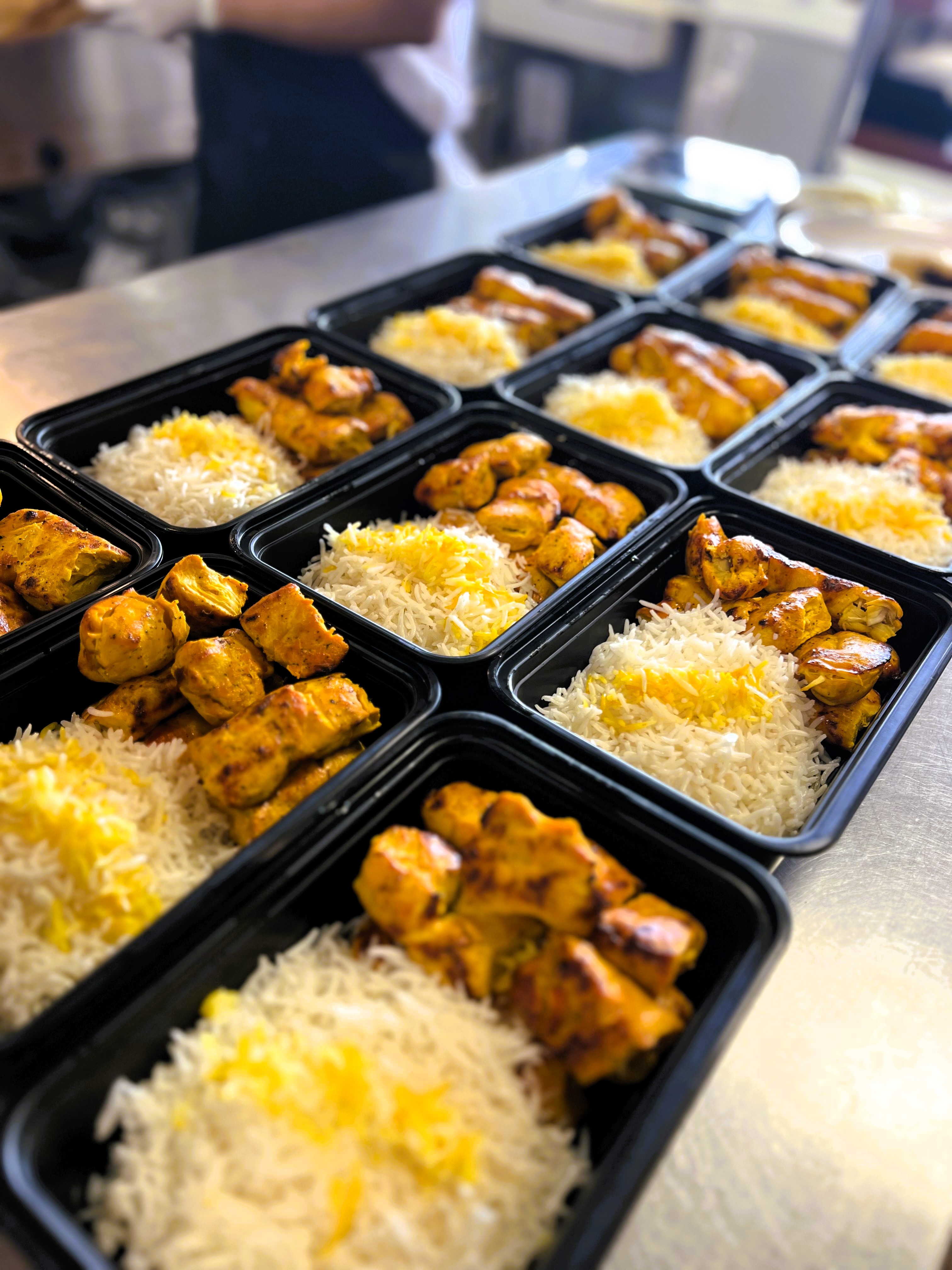 Rows of Chop Kabob meal prep containers — grilled chicken with saffron basmati rice, portioned and ready
