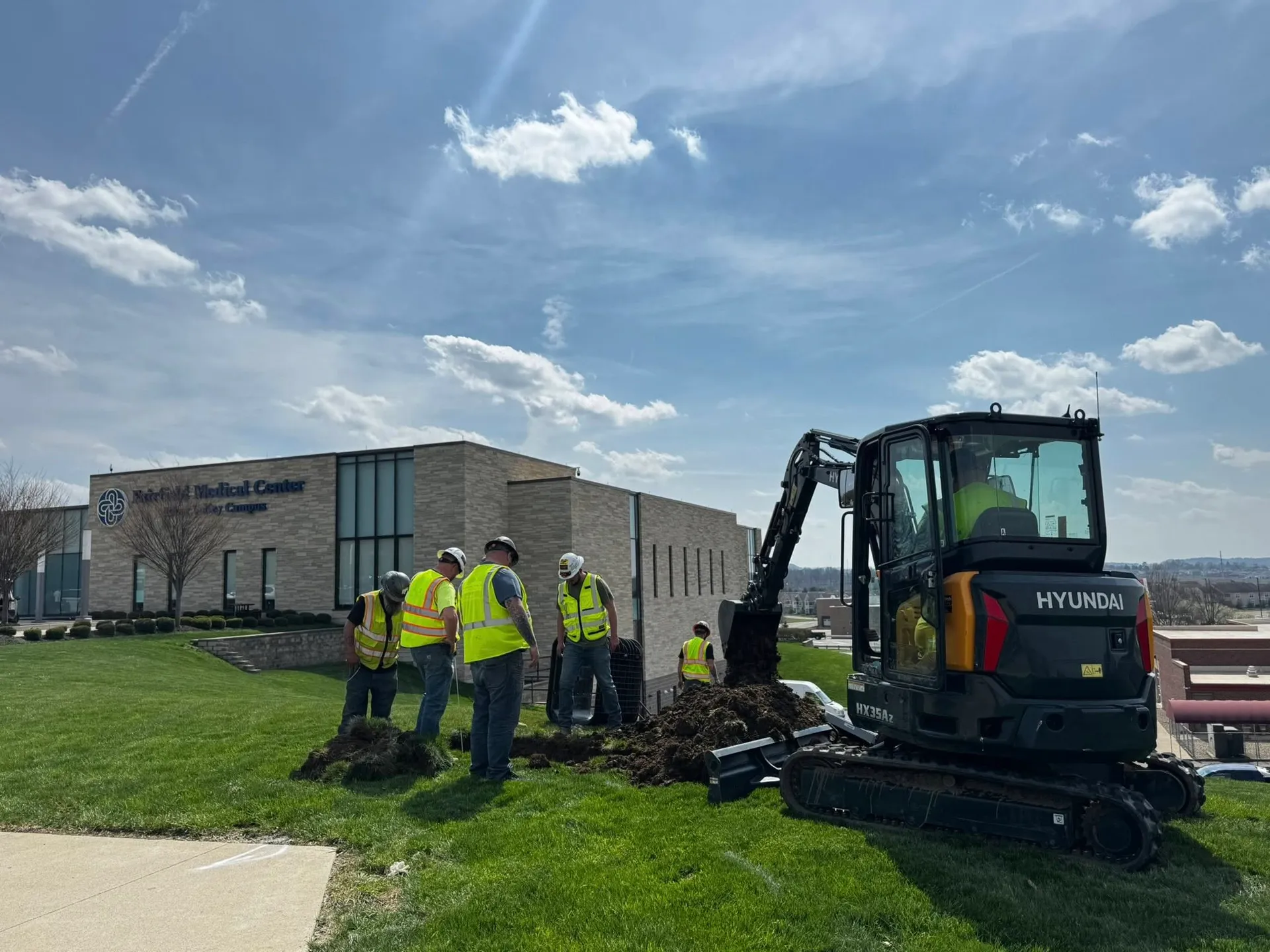Excavation crew with mini excavator at a commercial job site