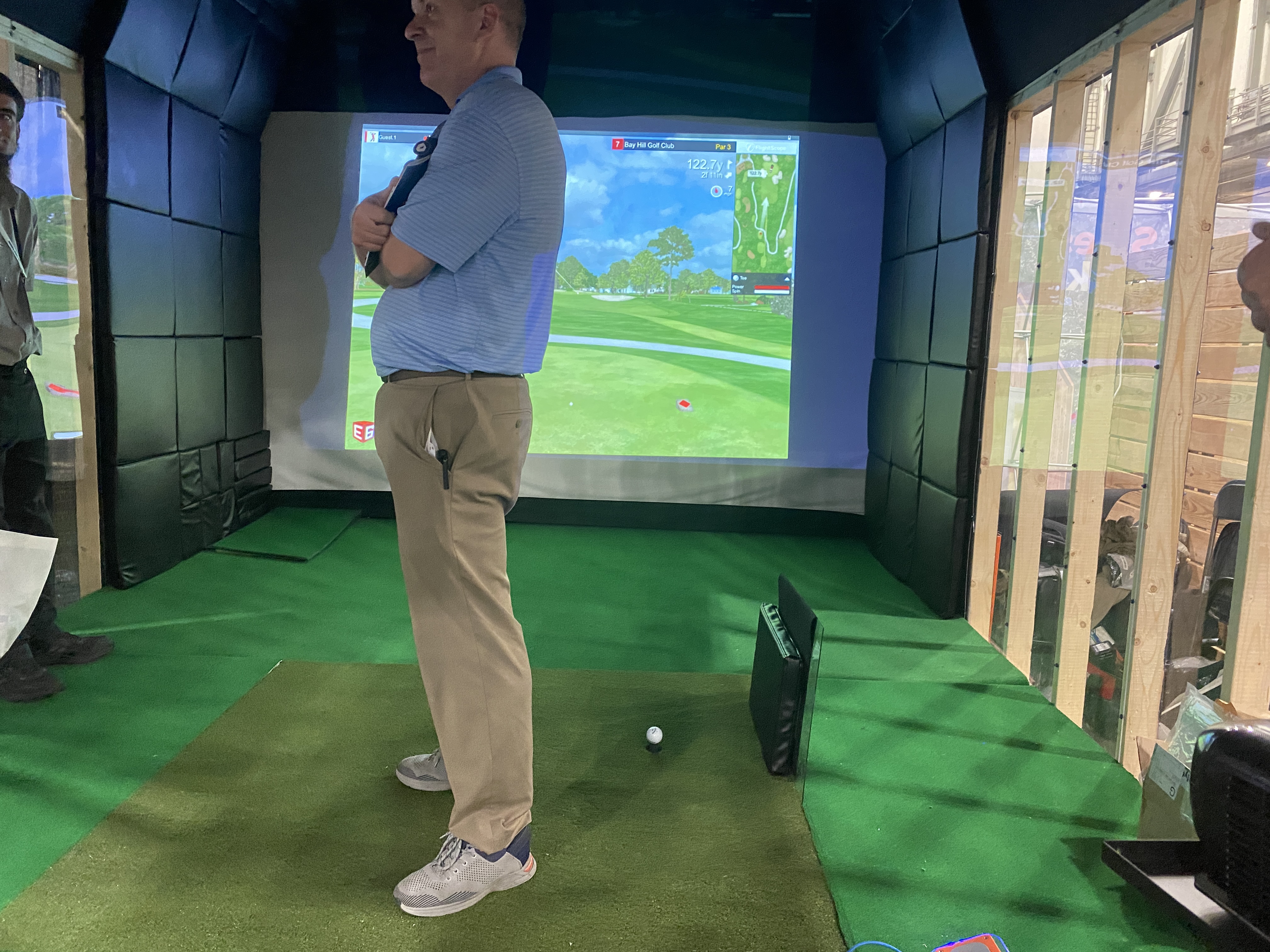 A golfer mid-round inside a finished shed simulator, a course live on the impact screen.