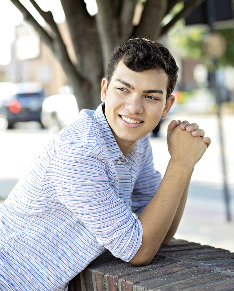 Senior boy in a checked shirt smiling with his hands clasped. Senior boy in a checked shirt smiling with his hands clasped.