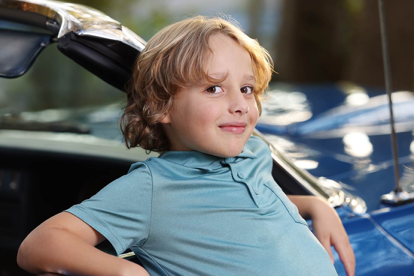 Youngest Moyer son with blond hair seated beside a car. Youngest Moyer son with blond hair seated beside a car.