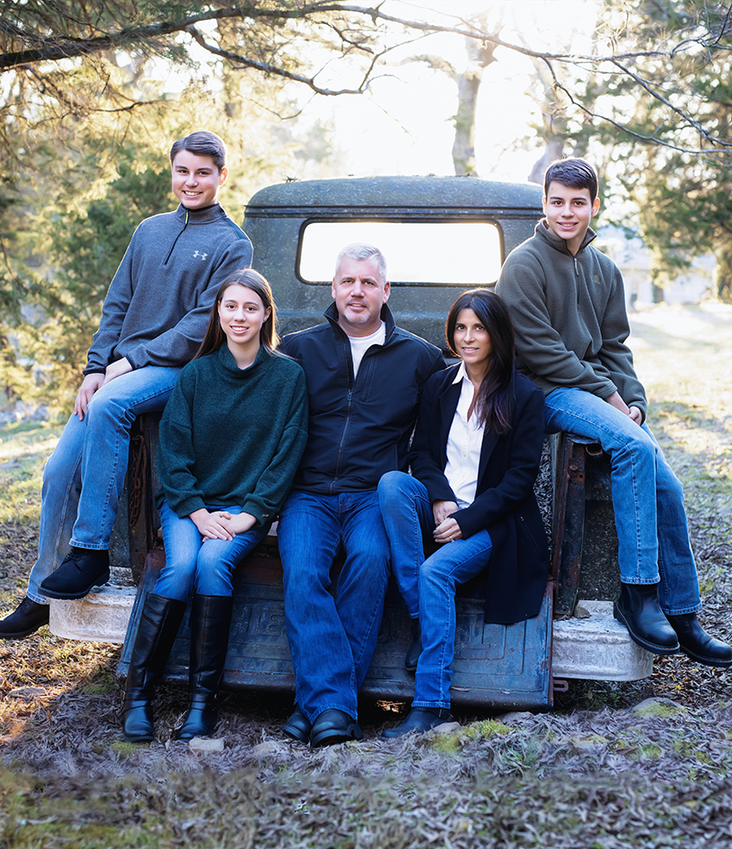 Williams family gathered on and around the front of a vintage car. Williams family gathered on and around the front of a vintage car.