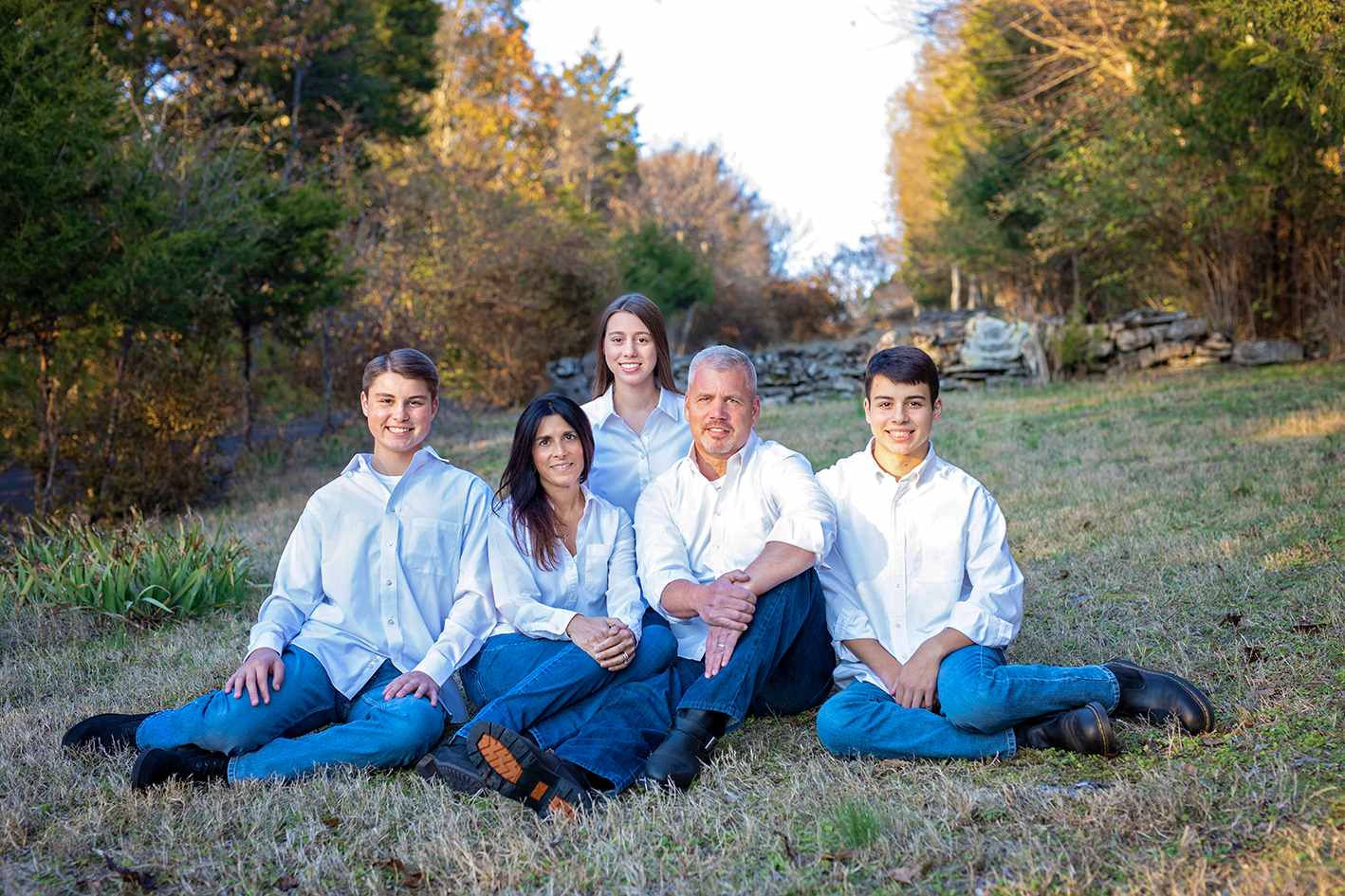 Williams family seated together in a grassy garden with autumn trees. Williams family seated together in a grassy garden with autumn trees.