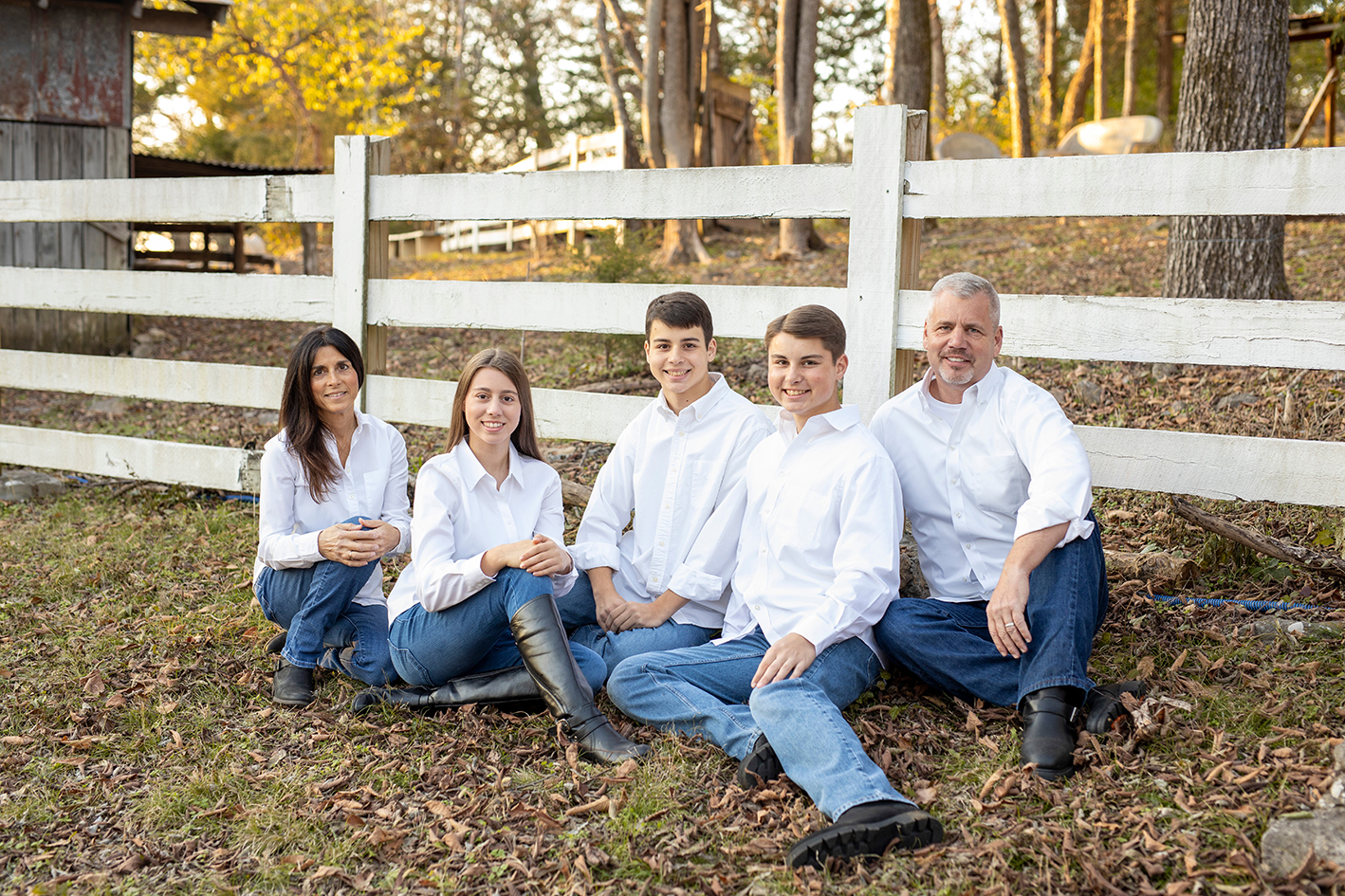 Williams family in white shirts sitting beside a white fence. Williams family in white shirts sitting beside a white fence.