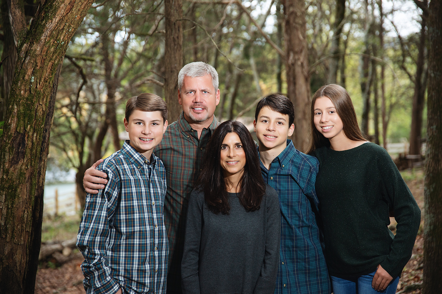 Williams parents with their three younger children gathered among trees. Williams parents with their three younger children gathered among trees.