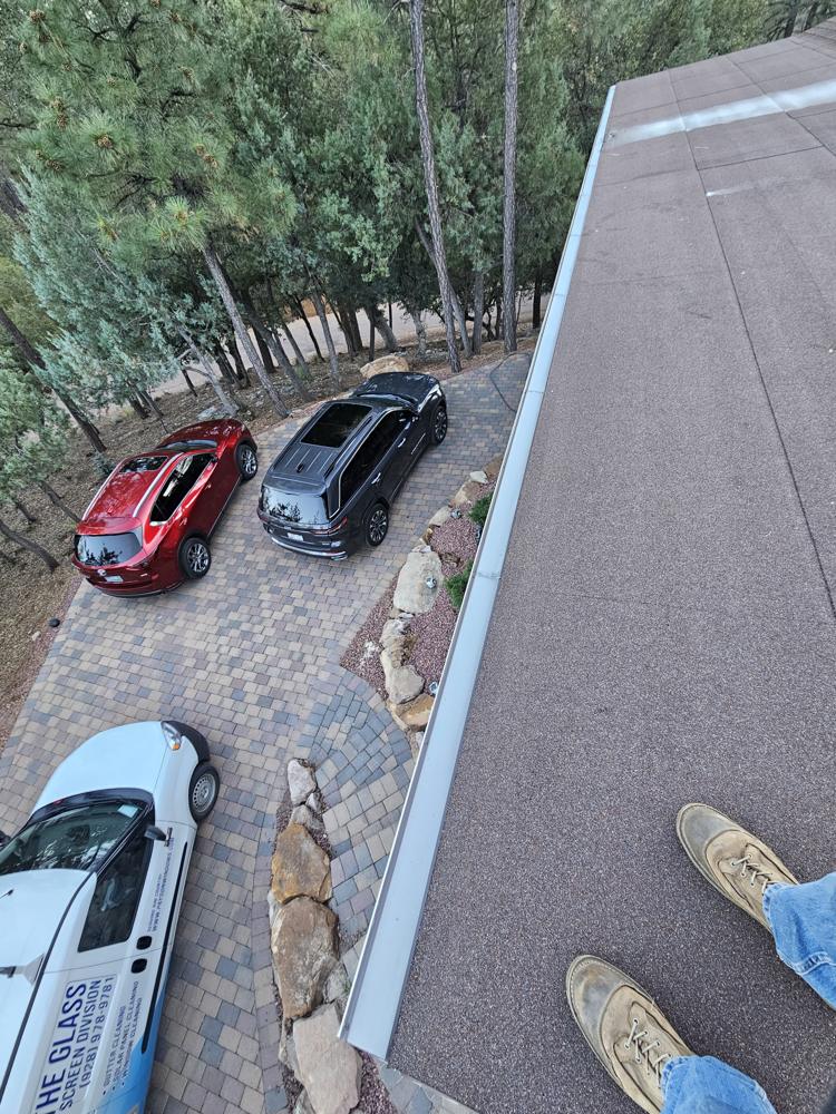 Installer's boots on a roof above a driveway