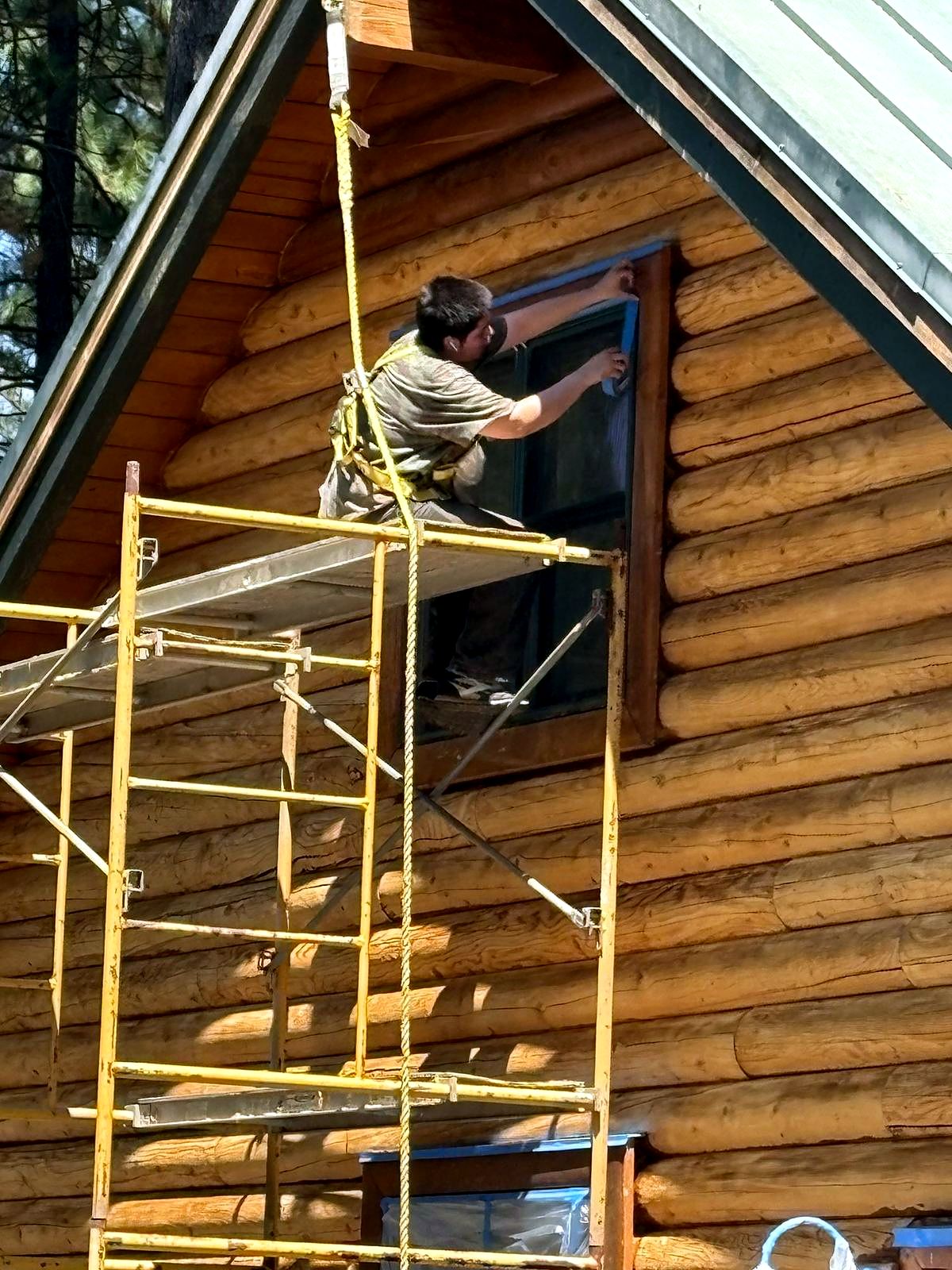 Crew member on scaffolding taping off a window