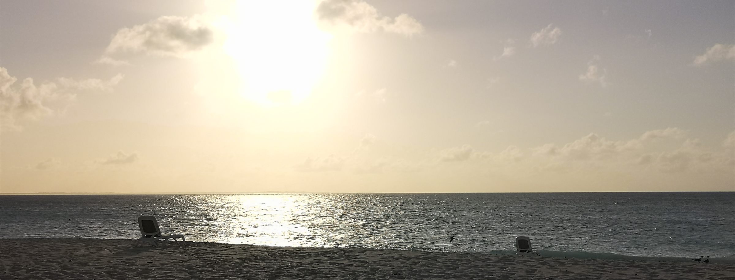 Sunset over a quiet tropical beach with empty loungers