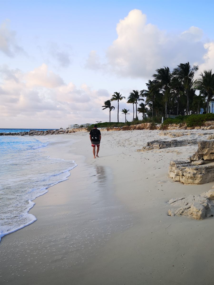 A traveller walking a quiet Caribbean beach at sunrise