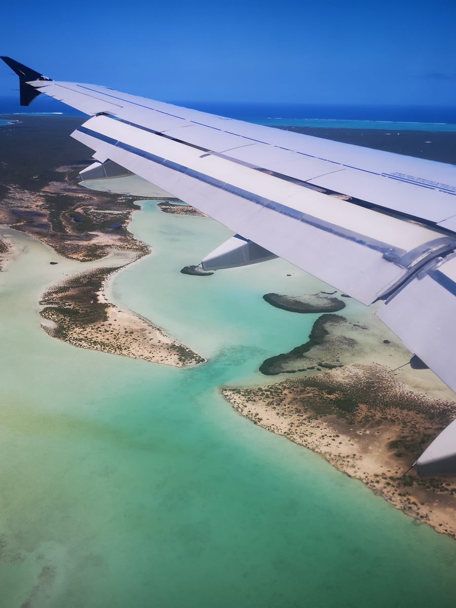 View from a plane window over turquoise Caribbean shallows